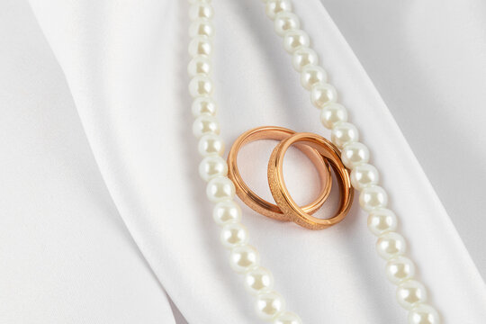 Elegant wedding rings on satin with pearls