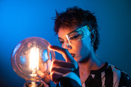Cyberpunk young woman using vr visor with glowing bulb