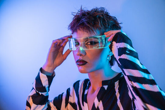 Cyberpunk young woman using futuristic virtual reality visor