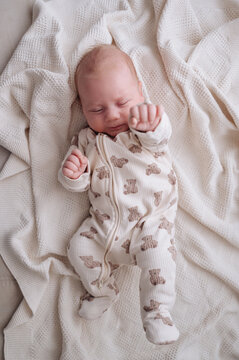 Sleeping 1 month baby boy in patterned onesie on blanket