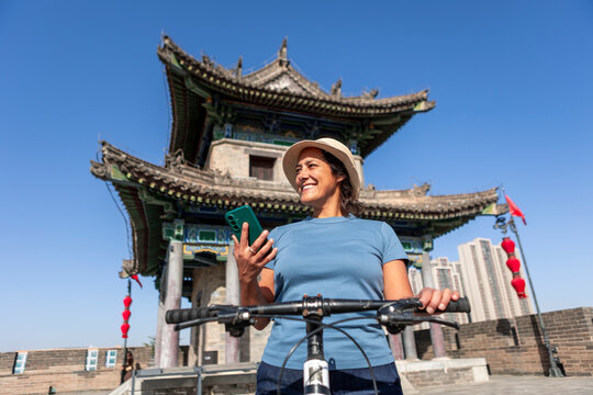 Woman biking on Xi'an ancient wall using smartphone
