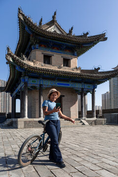 Woman biking at Xi'an ancient city wall using smartphone