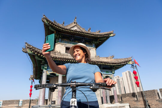 Woman biking on Xi'an ancient wall taking smartphone selfie