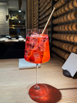 Aperol cocktail with ice and straw in modern bar setting