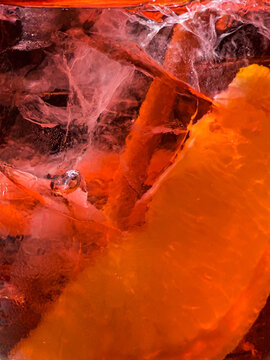 Macro of Aperol cocktail with ice cubes and citrus slice