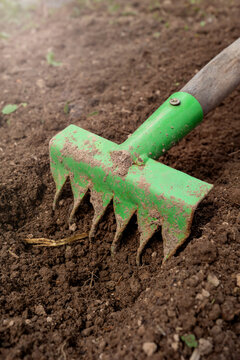 Green garden tool resting on soil ready for farming tasks