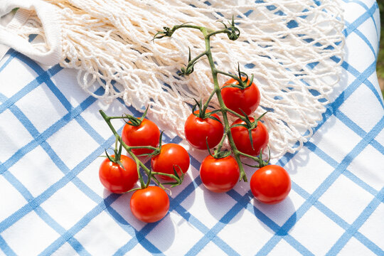Fresh cherry tomato on checkered tablecloth with net bag