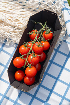 Fresh cherry tomato in black tray on blue check cloth