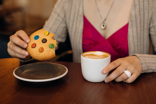 Woman enjoying cookie and coffee at cozy cafe table