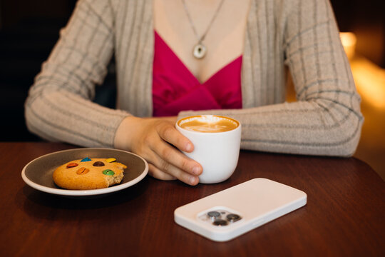 Woman enjoying coffee and cookie at cozy cafe table
