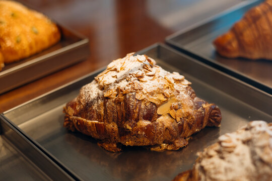 Almond croissant topped with sliced almonds in bakery case