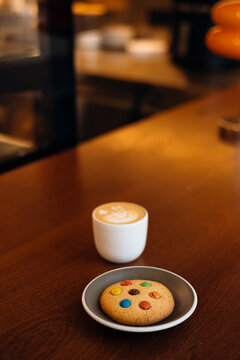 Cozy cafe table with latte art and cookie on plate