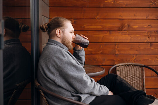 Man sipping morning coffee outside on cozy cafe terrace