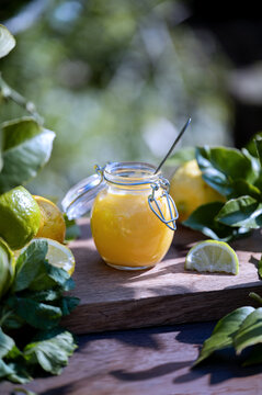 Sweet lemon curd in glass jar with fresh lemons on board