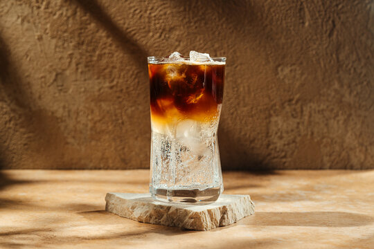 Espresso tonic in a glass with ice on a stone coaster