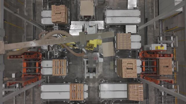 M&aacute;quina industrial automatizada moviendo cajas en f&aacute;brica, sistema de transporte y manipulaci&oacute;n de materiales en planta de producci&oacute;n