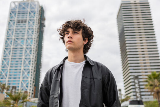 Curly-haired man in urban lifestyle portrait between towers