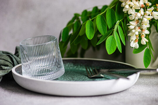 Minimal table setting with acacia flower and glassware