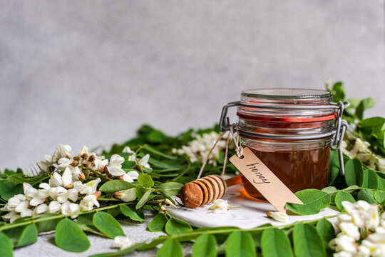Acacia honey jar with dipper and white flower on table