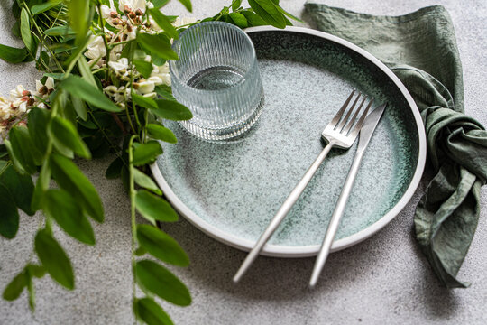 Minimal table setting with acacia blossom and rustic plate