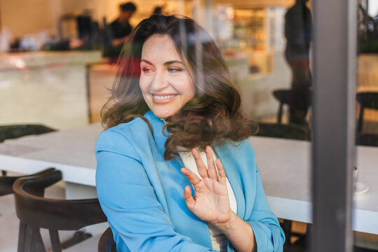 Smiling businesswoman waving in a cafe setting