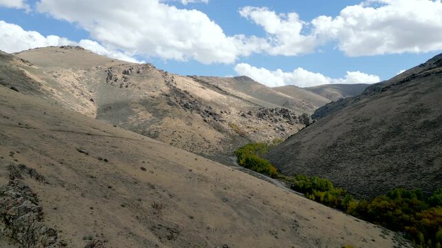 Aerial views of a rocky hillside just outside of Winnemucca Nevada with patches of color in the vegetation at the bottom of the mountains.