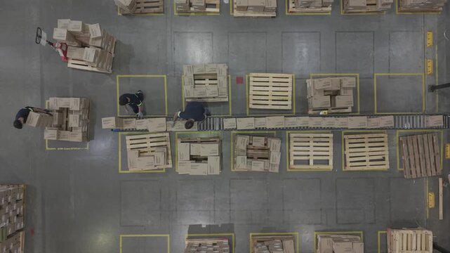 F&aacute;brica en funcionamiento con cinta transportadora y cajas en proceso, obreros trabajando en producci&oacute;n industrial vista cenital, footage industria, trabajo, industrializaci&oacute;n, desarrollo