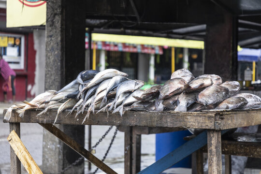 Douala, Cameroon - 28 April 2025: View of fresh fish stacked on a rustic wooden table at an outdoor market stall.