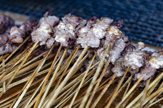 Douala, Cameroon - 28 April 2025: View of grilled meat skewers seasoned with spices and cooked on wooden sticks, a popular street food in the city.