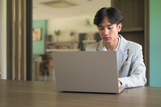 Portrait of non-binary Thai Isan professional using laptop at desk