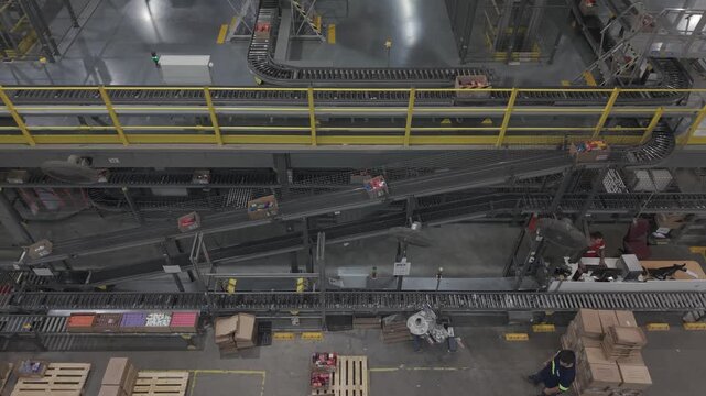 F&aacute;brica en funcionamiento con cinta transportadora y cajas en proceso, obreros trabajando en producci&oacute;n industrial vista cenital, footage industria, trabajo, industrializaci&oacute;n, desarrollo
