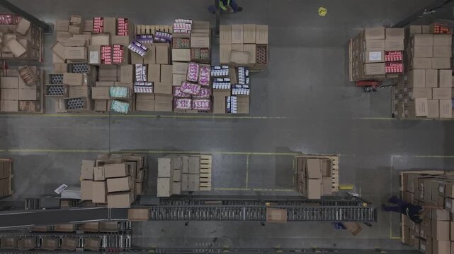 F&aacute;brica en funcionamiento con cinta transportadora y cajas en proceso, obreros trabajando en producci&oacute;n industrial vista cenital, footage industria, trabajo, industrializaci&oacute;n, desarrollo
