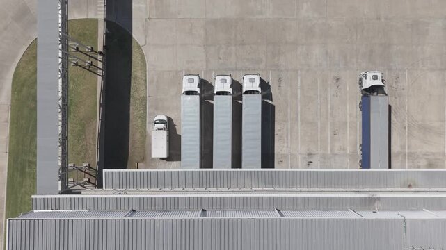 Camiones estacionados en centro log&iacute;stico, transporte y distribuci&oacute;n industrial vista a&eacute;rea de dron