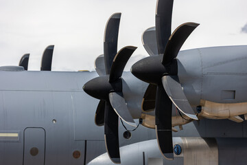 Naklejka premium Close view large turboprop propeller military transport aircraft dramatic cloudy sky. Powerful aerospace propulsion system engineering precision aerodynamic efficiency advanced aviation technology