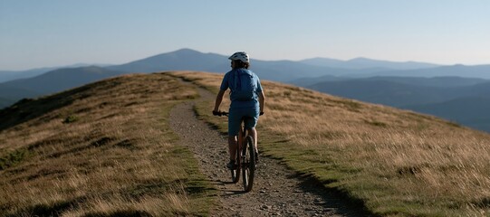 Fototapeta premium Trail cyclist riding along mountain ridge path under expansive sky