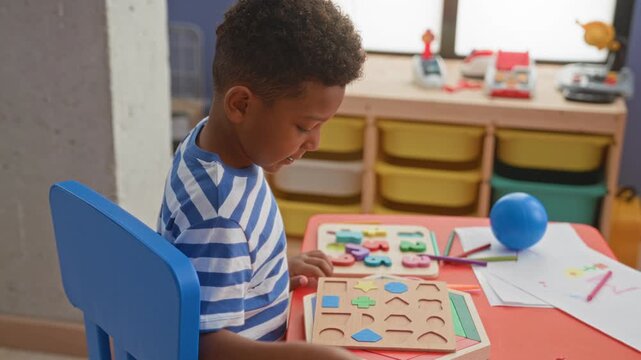 Boy placing wooden shape puzzle piece by hand at a preschool playroom table inside a building; concentration learning play.
