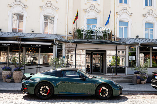 Luxury sports Porsche 911 Targa 4 GTS car parked outside Radisson Collection Astorija hotel in Vilnius, Lithuania with people at the hotel entrance