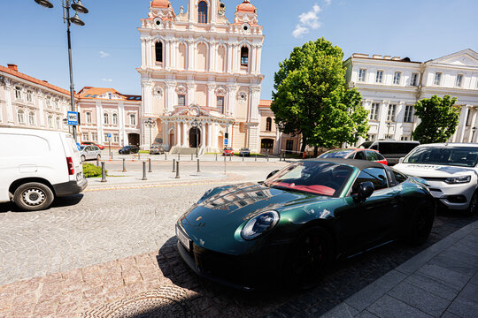 Luxury sports Porsche 911 Targa 4 GTS car parked on a cobblestone street in front of a historic St. Casimir church in Vilnius, Lithuania city center
