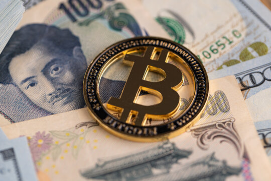 Gold Bitcoin coin on US dollar and Japanese yen banknotes