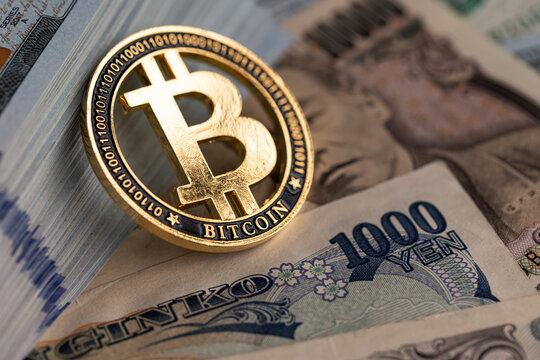 Gold Bitcoin coin on US dollar and Japanese yen banknotes