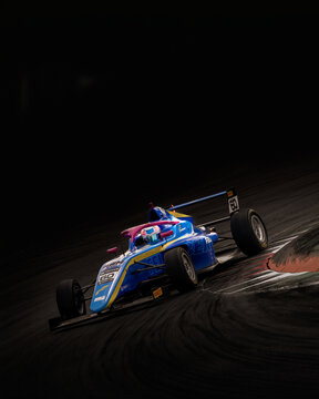 Single-seater formula race car attacks a corner at Monza Circuit, showcasing speed, precision, grip, and dramatic motorsport action against a dark, high-contrast background.