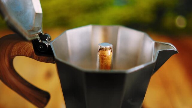 Geyser coffee maker. Process of making Italian espresso in a moka pot. Close up shot of hot espresso coffee brewing and flowing out of the center column nozzle of an open moka pot. Italian espresso ma