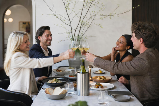 Photorealistic generative AI stock image of friends wine toast in a modern restaurant with warm hospitality atmosphere and commercial food photography style