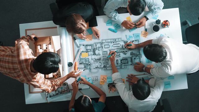 Top aerial view of project manager or civil engineer writing at blueprint and planning building design. Aerial view of architect working together at meeting table with document placed. Alimentation.