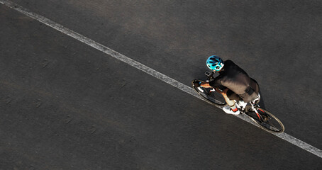 Aerial top drone high view of sporty male Cyclist with helmet shorts riding cross bicycle isolated on asphalt road background  showing man on racing bicycle riding Motion tour de france Active wear © Maxim Chuev