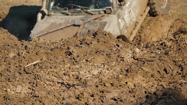 Close up of 4x4 wheel spinning in deep mud during extreme off road competition. Rugged vehicle covered in dirt navigates difficult terrain. Low angle view captures action and power