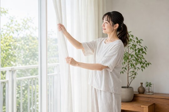 ベランダ窓を開ける女性の朝の換気
