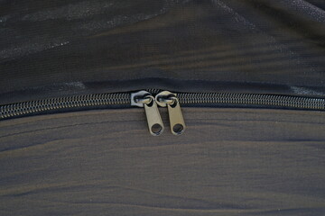 Macro shot of heavy-duty dual metal zipper pulls on a black camping hammock. © Imageologist