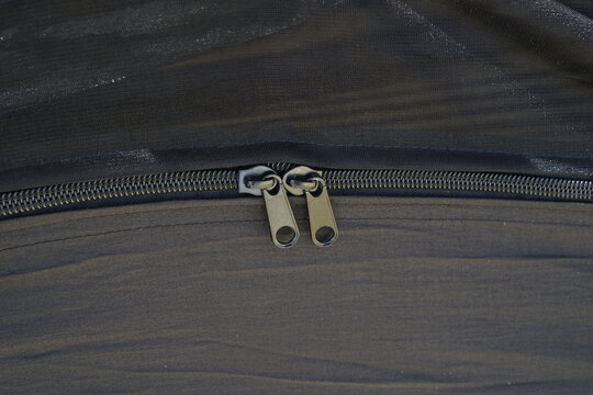 Macro shot of heavy-duty dual metal zipper pulls on a black camping hammock.