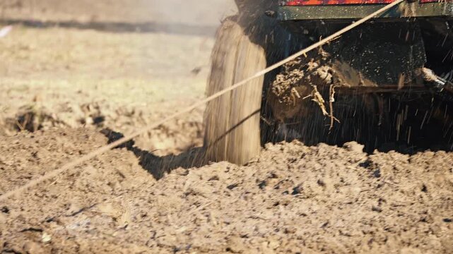 A co-pilot holds a special anchor while standing in thick, wet mud during an extreme competition. A close-up of his legs and recovery rope. A demonstration of challenge and endurance in motorsports